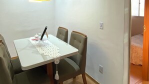 Uma área de refeições com mesa e cadeiras, uma luminária pendente e uma porta que dá para outro cômodo.