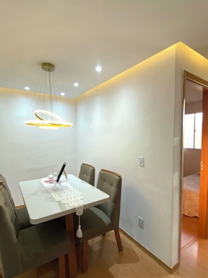 A dining area with a table and chairs, a pendant light, and a door leading to another room. - Apartment near Galeão Airport • 2 bedrooms • With 1 vacancy (Duque de Caxias)