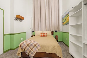 Une chambre à coucher avec un lit, une table de chevet, une lampe, un tableau au mur et une armoire.