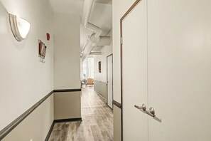 A corridor with a wooden floor, white walls, and doors on the right. - New Cozy 3BR Apt - Perfect for Families & Groups (Indianapolis)