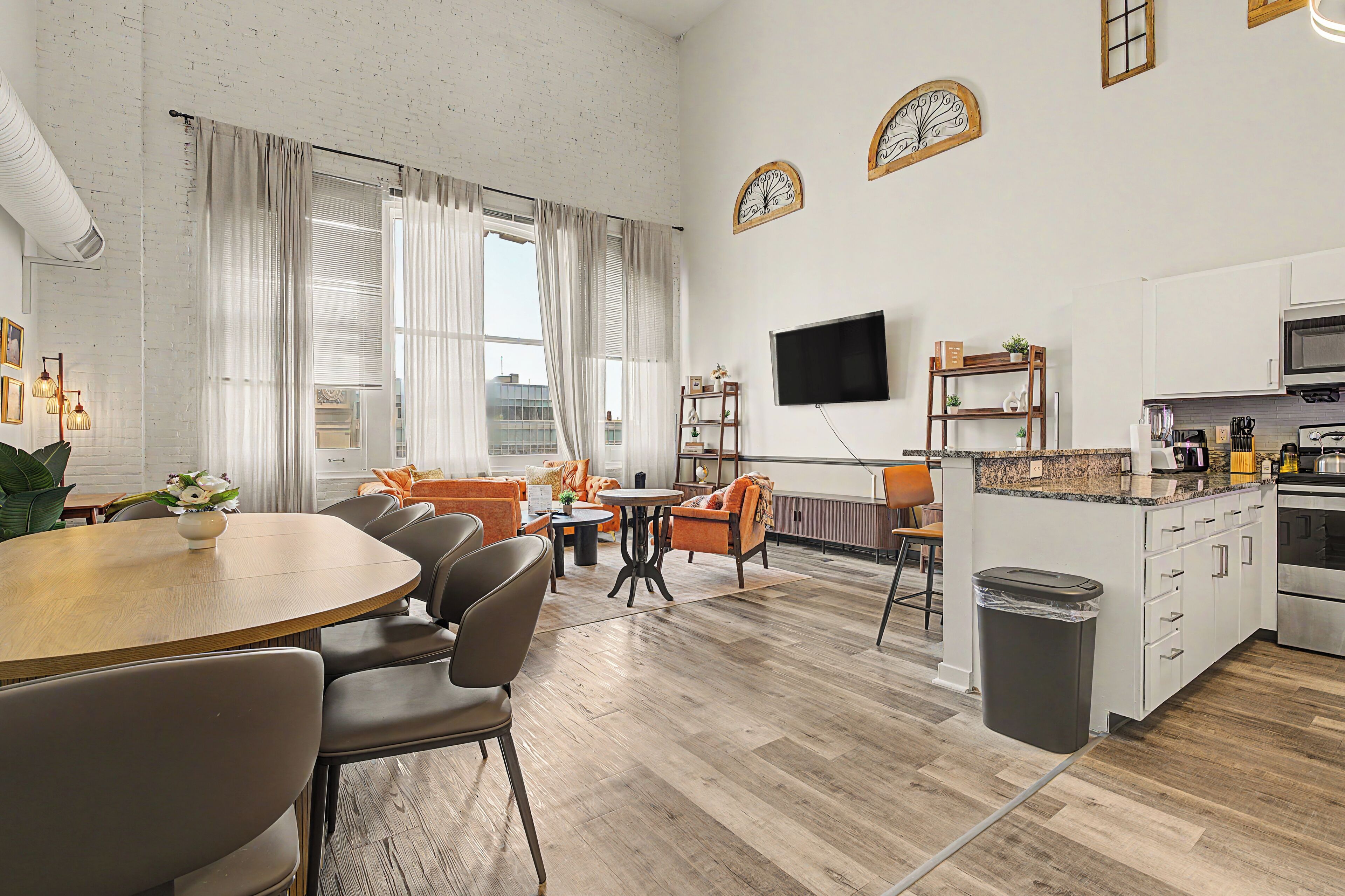 A modern kitchen with a flat-screen TV, wooden cabinets, and a granite countertop.