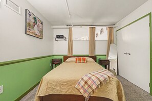 A bedroom with a bed, a nightstand, a dresser, a window with curtains, and a wall-mounted picture. - New Cozy 3BR Apt - Perfect for Families & Groups (Indianapolis)