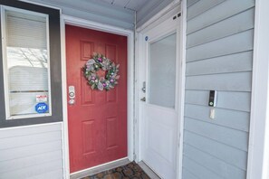 A red door with a wreath, a pet alert sign, and a doorbell.