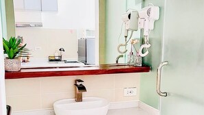 Ein Badezimmer mit weißem Waschbecken, Holzschränken, einem Spiegel und einer Duschkabine aus Glas.