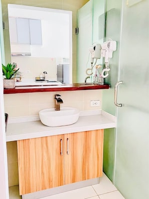 Un bagno con lavandino bianco, mobili in legno, uno specchio e cabina doccia in vetro.
