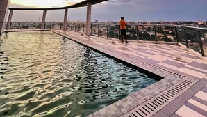 Ein Pool auf dem Dach mit Blick auf eine Stadtlandschaft bei Sonnenuntergang.