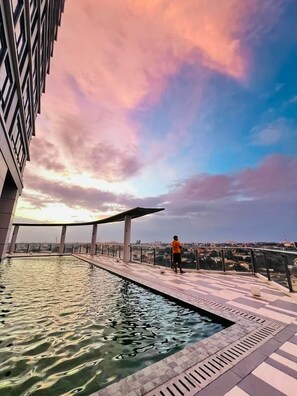 Una piscina sul tetto con vista sulla città al tramonto.