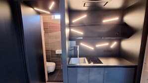 Una cocina compacta con diseño moderno, que incluye una estufa integrada y un lavamanos.