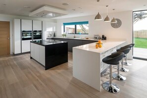 Une cuisine moderne dotée d’un îlot central, de tabourets de bar et d’une grande fenêtre.