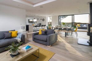 Un salon moderne comprenant un canapé, un fauteuil, une table basse et un coin repas avec des chaises et une table.