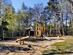 A playground with a slide and swings in a wooded area. - Outdoors Holten - Skydeck Cabin by Interhome (Holten)