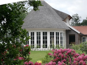 A house with a thatched roof, a covered porch with multiple windows, and a brick exterior. - Outdoors Holten - Skydeck Cabin by Interhome (Holten)
