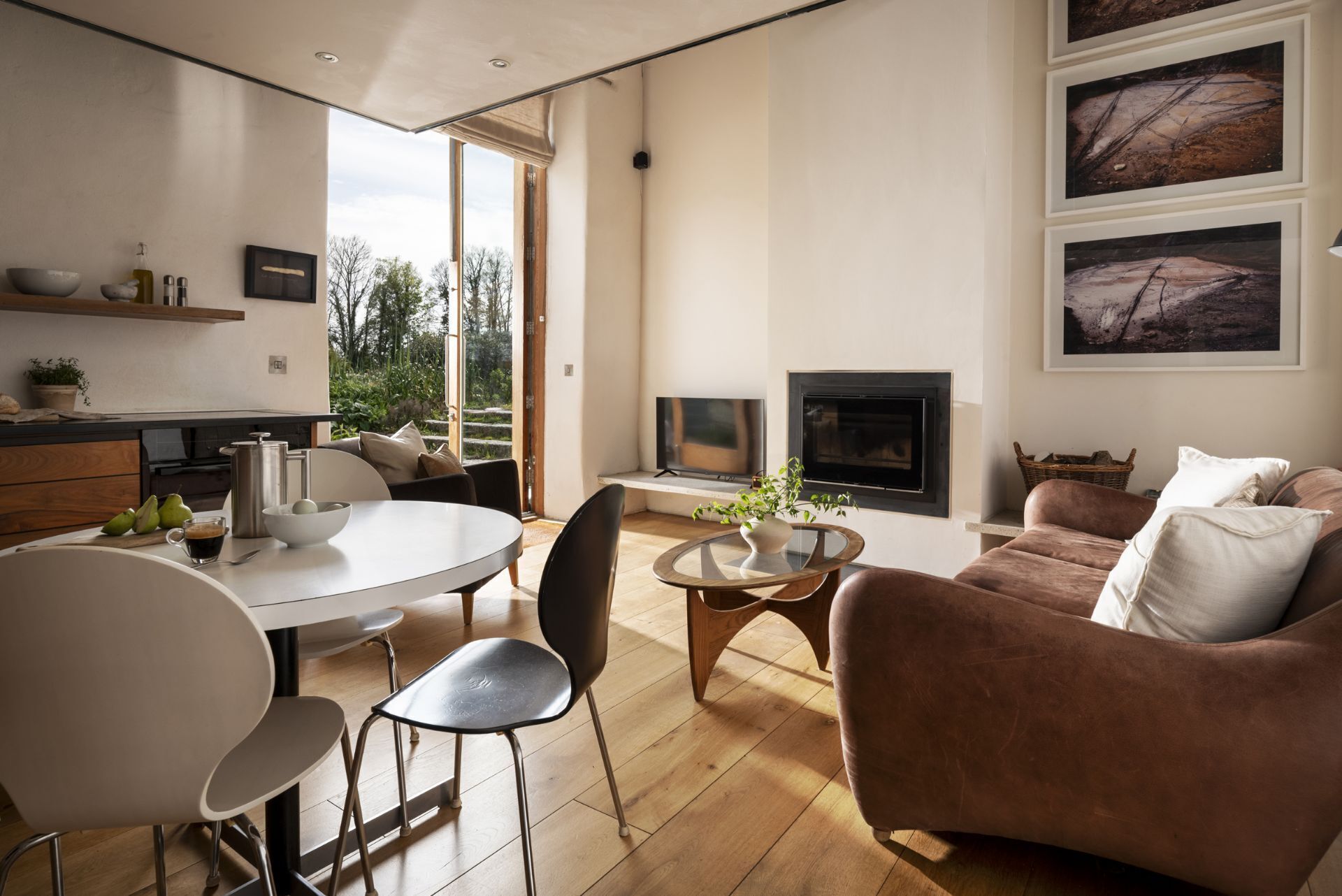A modern living room with a fireplace, a dining area with a round table and chairs, and a sofa.