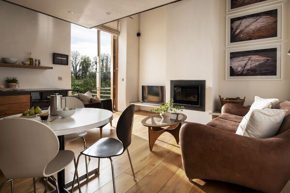 Un salon moderne avec une cheminée, un coin repas avec une table ronde et des chaises, et un canapé.