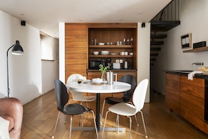 A modern kitchen with wooden cabinetry, a dining table with chairs, and a staircase. - Howthere Barn - sleeps 2 guests  in 1 bedroom (Helford)