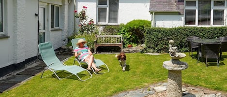 Il s’agit d’une propriété résidentielle dotée d’une pelouse bien entretenue, d’une fontaine en pierre et d’un espace détente avec des chaises.