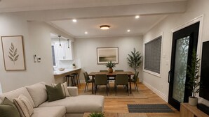 Ein modernes Wohnzimmer mit einem Ecksofa, einem Couchtisch und einem Essbereich mit Tisch und Stühlen.