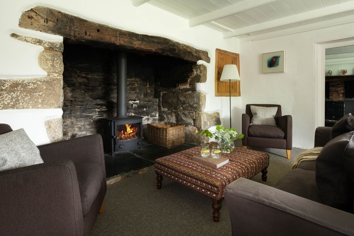 A cozy living room with a stone fireplace, comfortable seating, and a decorative table.