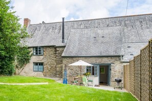 A stone house with a sloped roof, a patio with outdoor furniture, and a garden area. - Kestle Cottage - sleeps 4 guests  in 2 bedrooms (Helford)