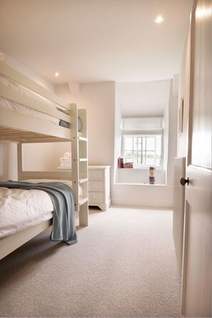 A bedroom with bunk beds, a bedside table, a window with a view, and a door. - Kestle Cottage - sleeps 4 guests  in 2 bedrooms (Helford)