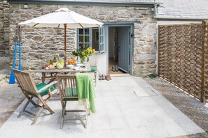 A stone building with a patio area featuring a table, chairs, and an umbrella. - Kestle Cottage - sleeps 4 guests  in 2 bedrooms (Helford)