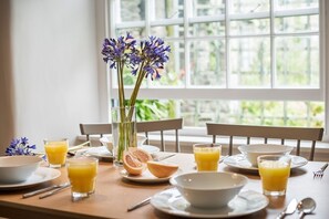 A breakfast table set with bowls, glasses of orange juice, and a vase with flowers. - Kestle Cottage - sleeps 4 guests  in 2 bedrooms (Helford)