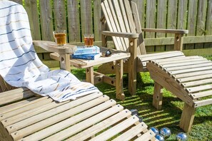 A wooden deck with two lounge chairs, a small table with drinks and books, and a covered area with a striped towel. - Lighthouse View - sleeps 4 guests  in 2 bedrooms (Hayle)