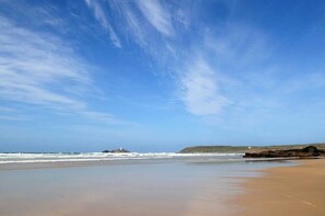 A beach with a clear sky, calm sea, and rocky outcrops. - Lighthouse View - sleeps 4 guests  in 2 bedrooms (Hayle)