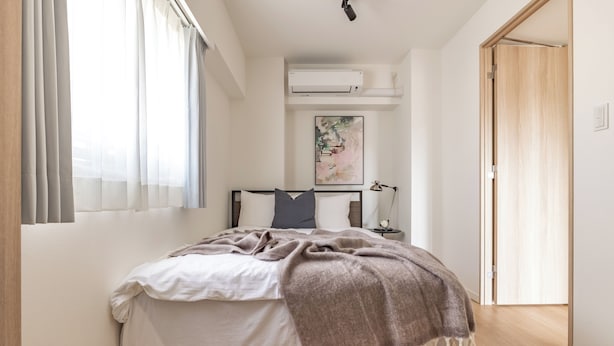 A bedroom with a bed, a bedside lamp, and an air conditioning unit. - Dash Living Asakusa East (Higashikomagata, Sumida City)