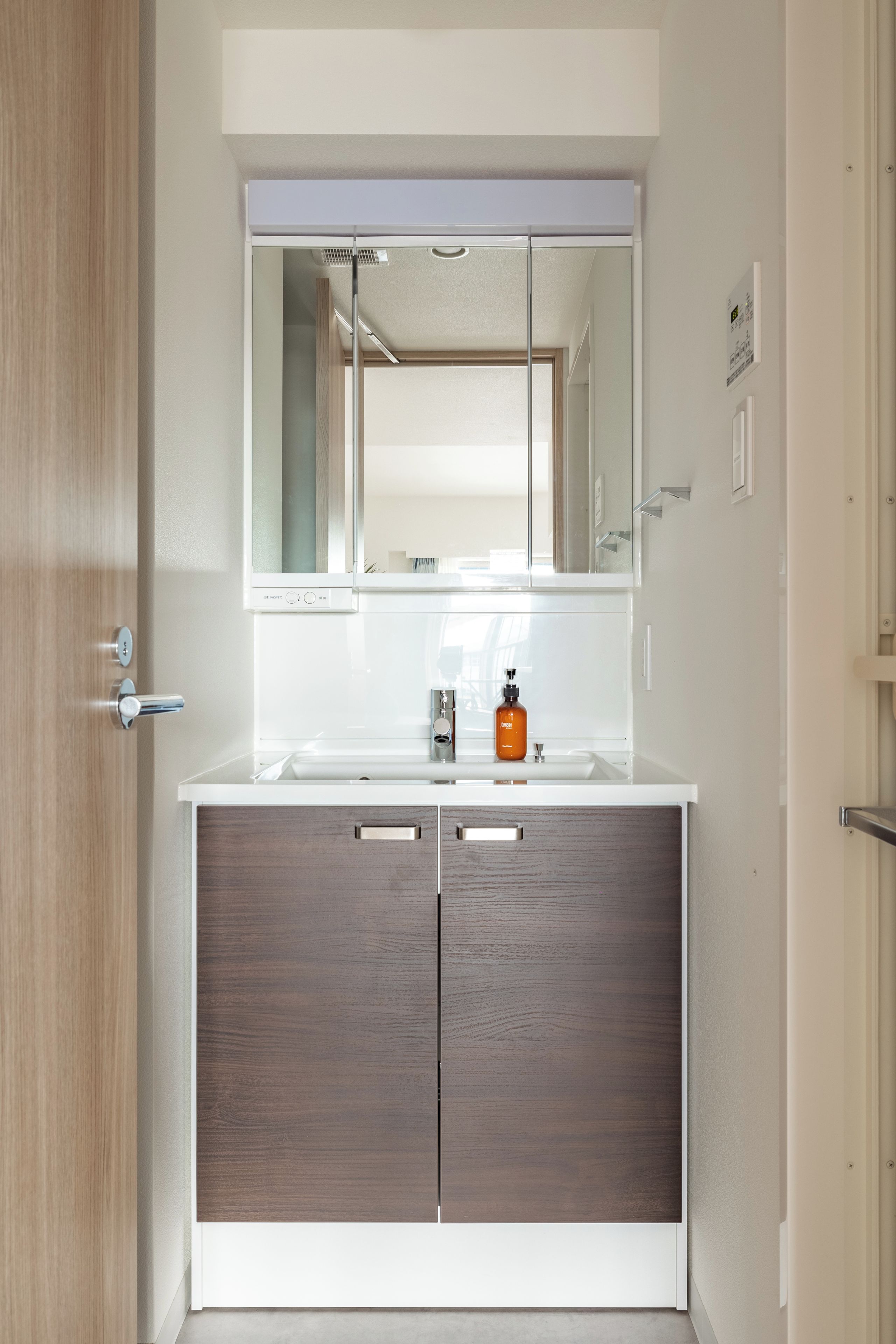 A bathroom with a white vanity, a mirror, and a bottle of soap.