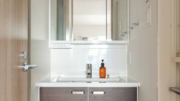 A bathroom with a white vanity, a mirror, and a bottle of soap.