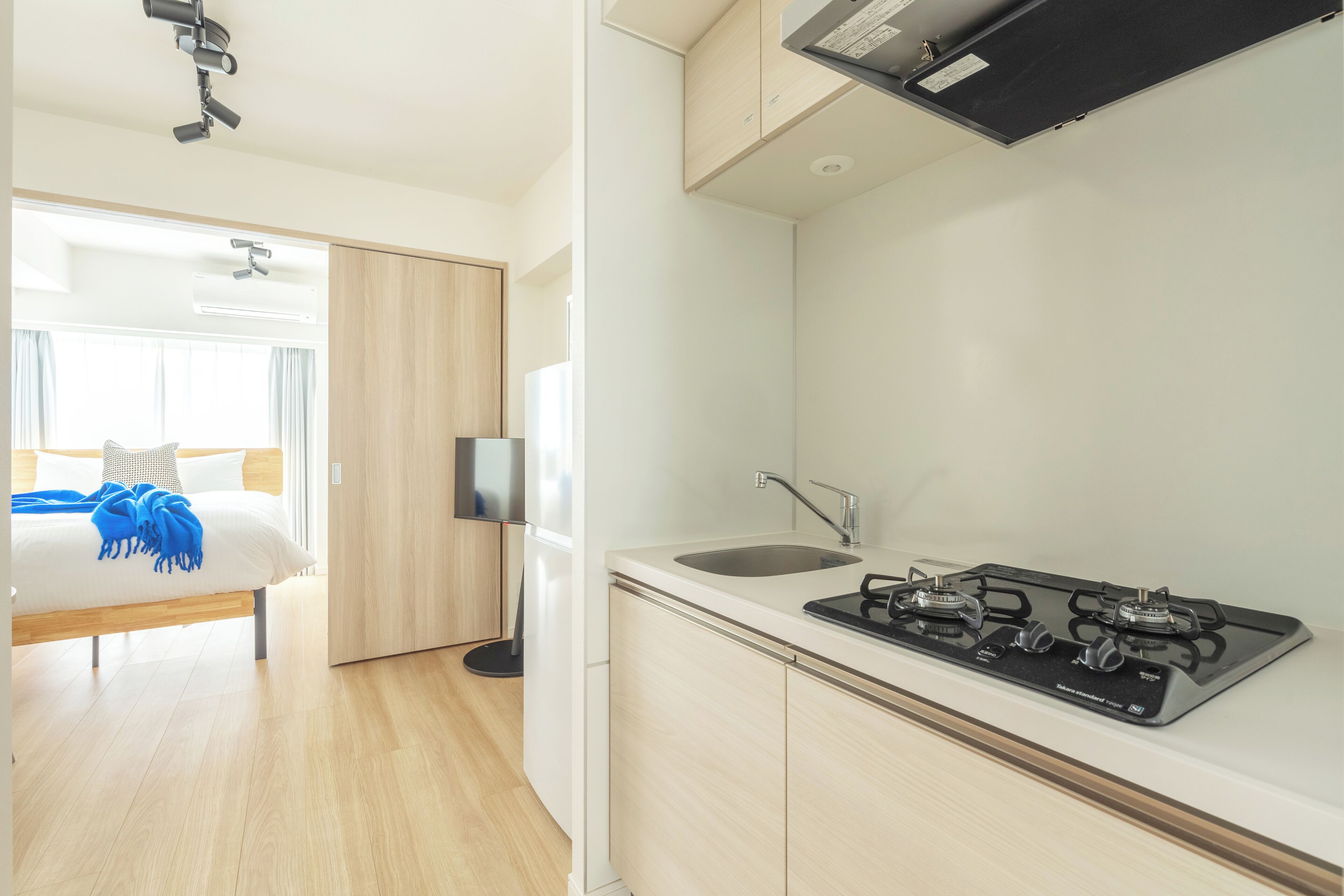 A modern kitchen with a gas stove, a sink, and a wooden cabinet.