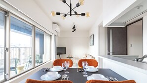 A modern dining area with a table set for two, a city view, and a contemporary chandelier. - Dash Living Asakusa East (Higashikomagata, Sumida City)