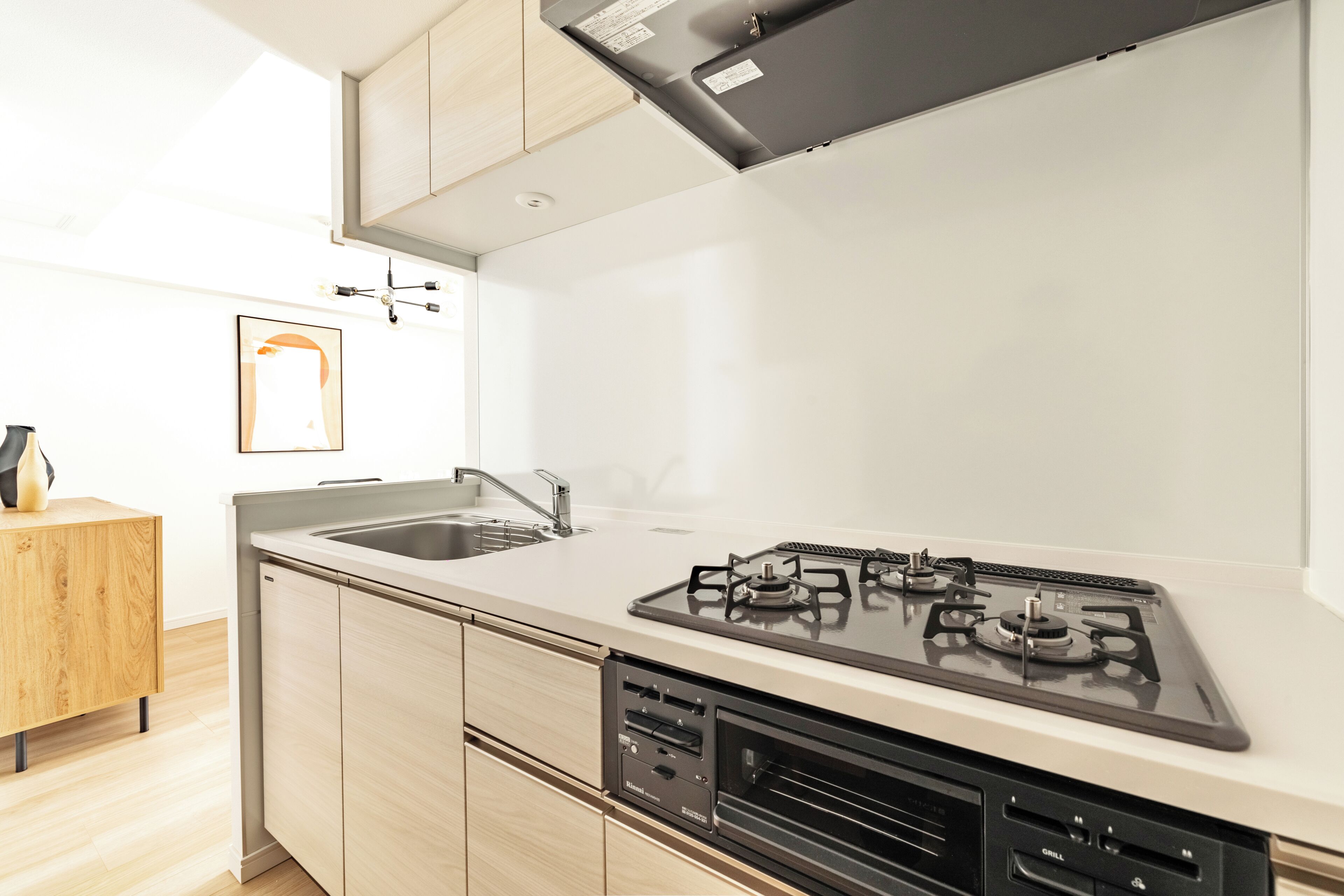 A modern kitchen with a gas stove, sink, and wooden cabinets.