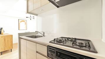 A modern kitchen with a gas stove, sink, and wooden cabinets.