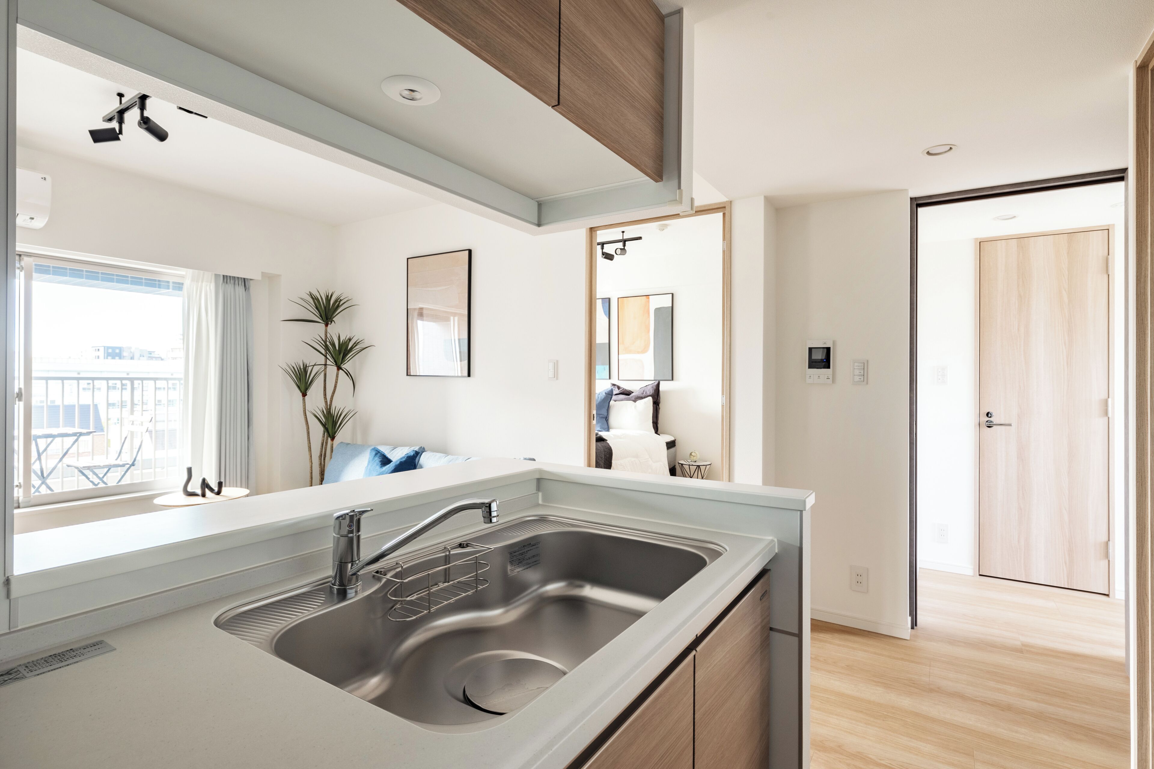A modern kitchen with a stainless steel sink, wooden cabinets, and a view to the outside.