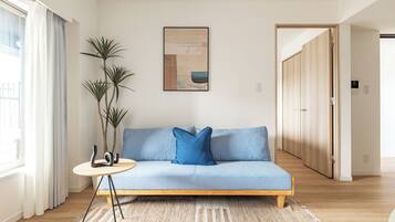 A modern living room with a light blue sofa, a round side table, and a large plant.