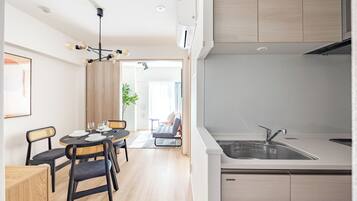 A modern kitchen with a sink, cabinets, and a dining area with a table and chairs.