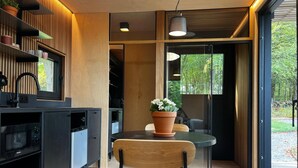 Una cocina moderna con microondas integrado, una silla de madera y una planta en maceta sobre una mesa.