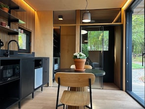 A modern kitchen with a built-in microwave, a wooden chair, and a potted plant on a table. - Romantic Tiny House in the Belgian Ardennes (Ferrières)