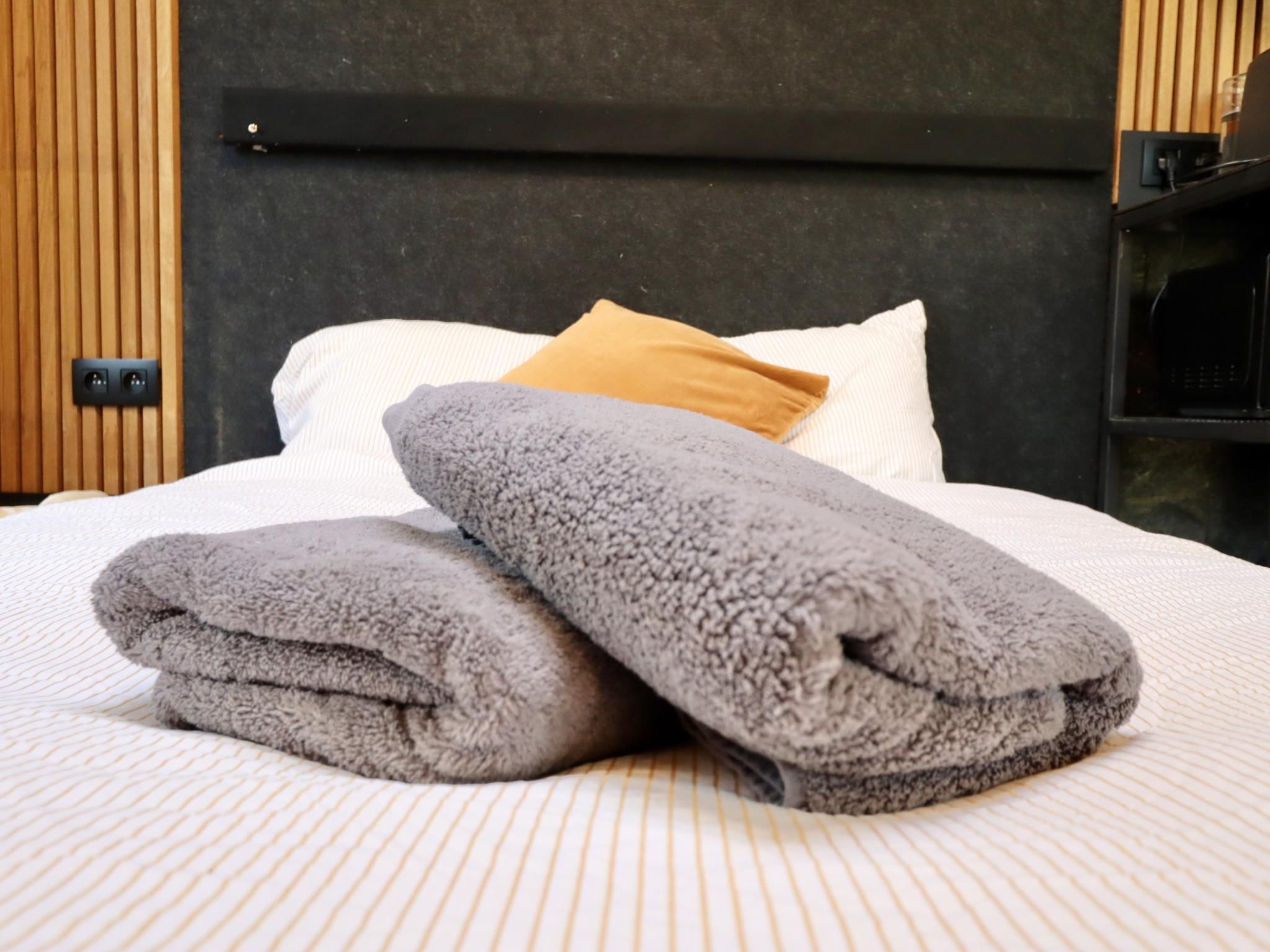 A neatly made bed with folded towels, a pillow, and a headboard.