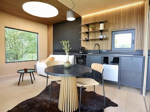 Een moderne keuken met een eethoek, een koffieapparaat en een groot raam.