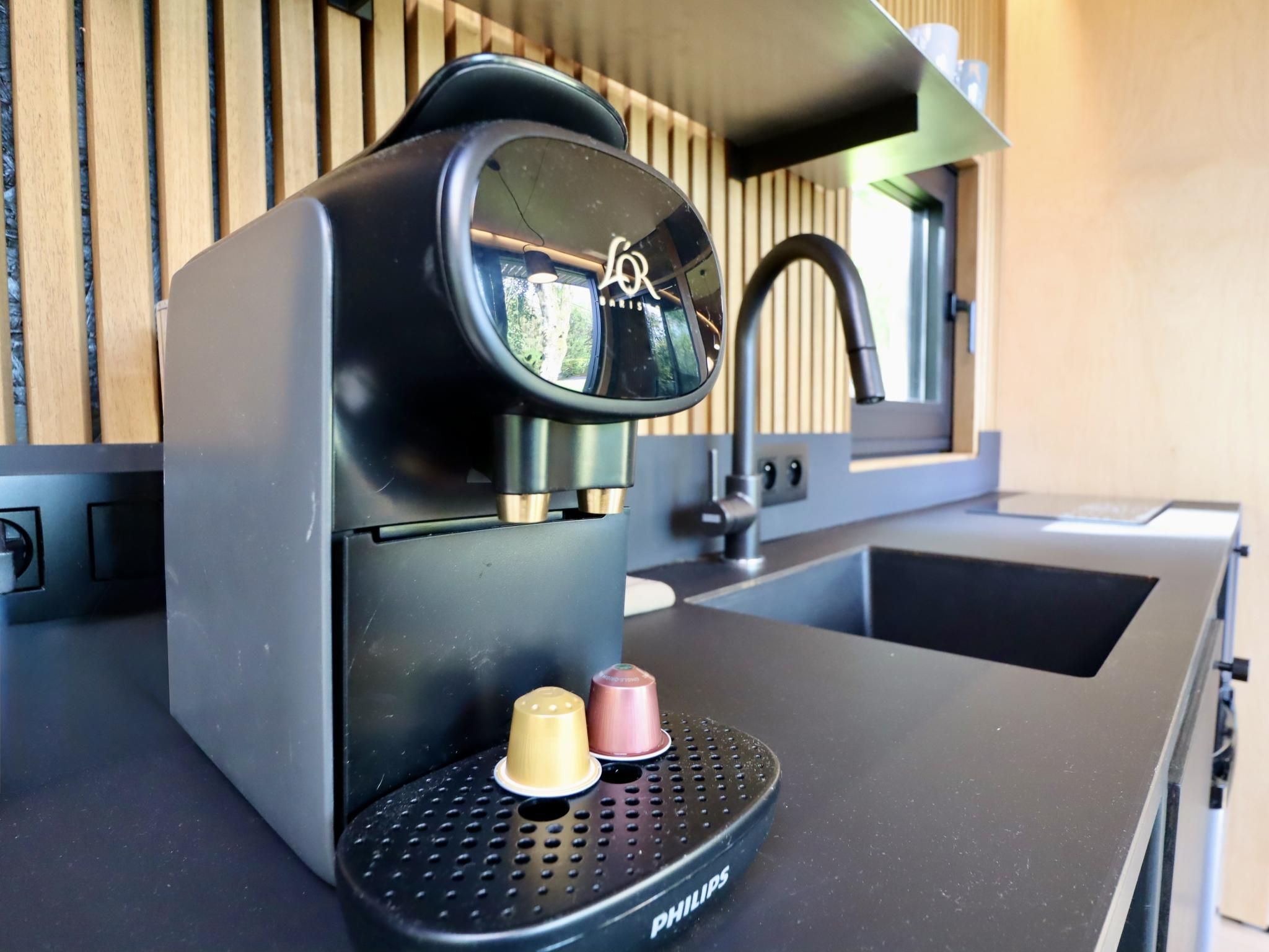 Une petite machine à café dotée d’un compartiment pour une seule dosette de café et d’un réservoir d’eau, posée sur un plan de travail de cuisine.