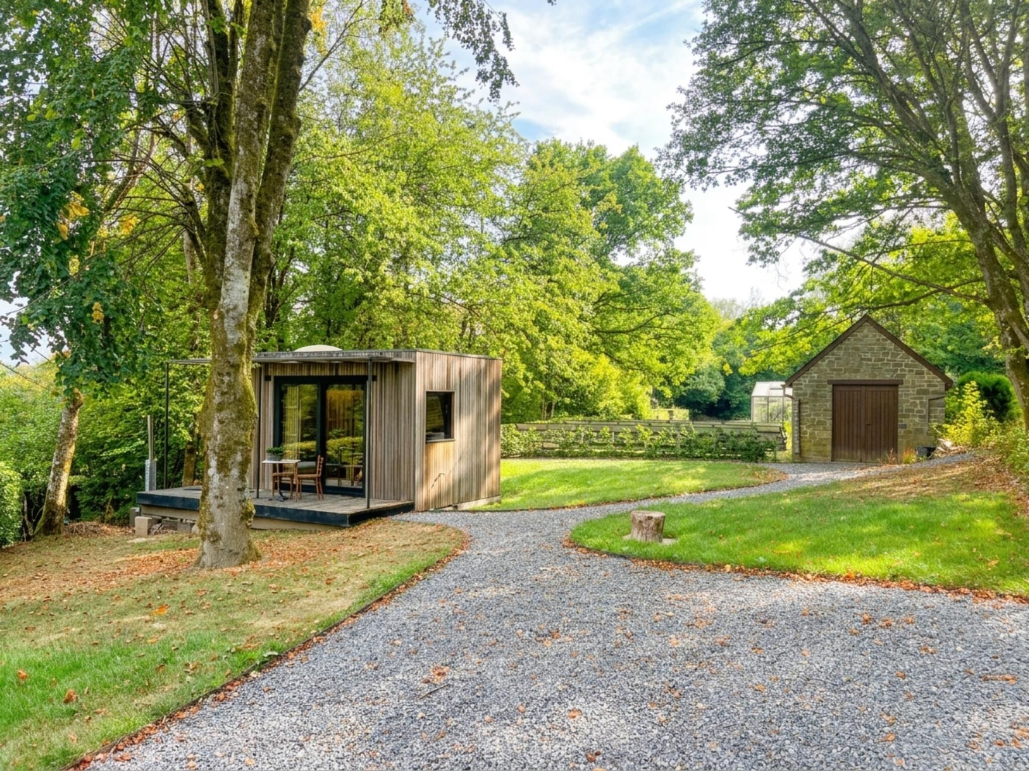 A gravel pathway leading to a wooden structure with a glass door, surrounded by lush greenery and trees.