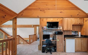 Un interno in legno con una cucina, una scrivania con un computer e una scala che conduce a un piano superiore.