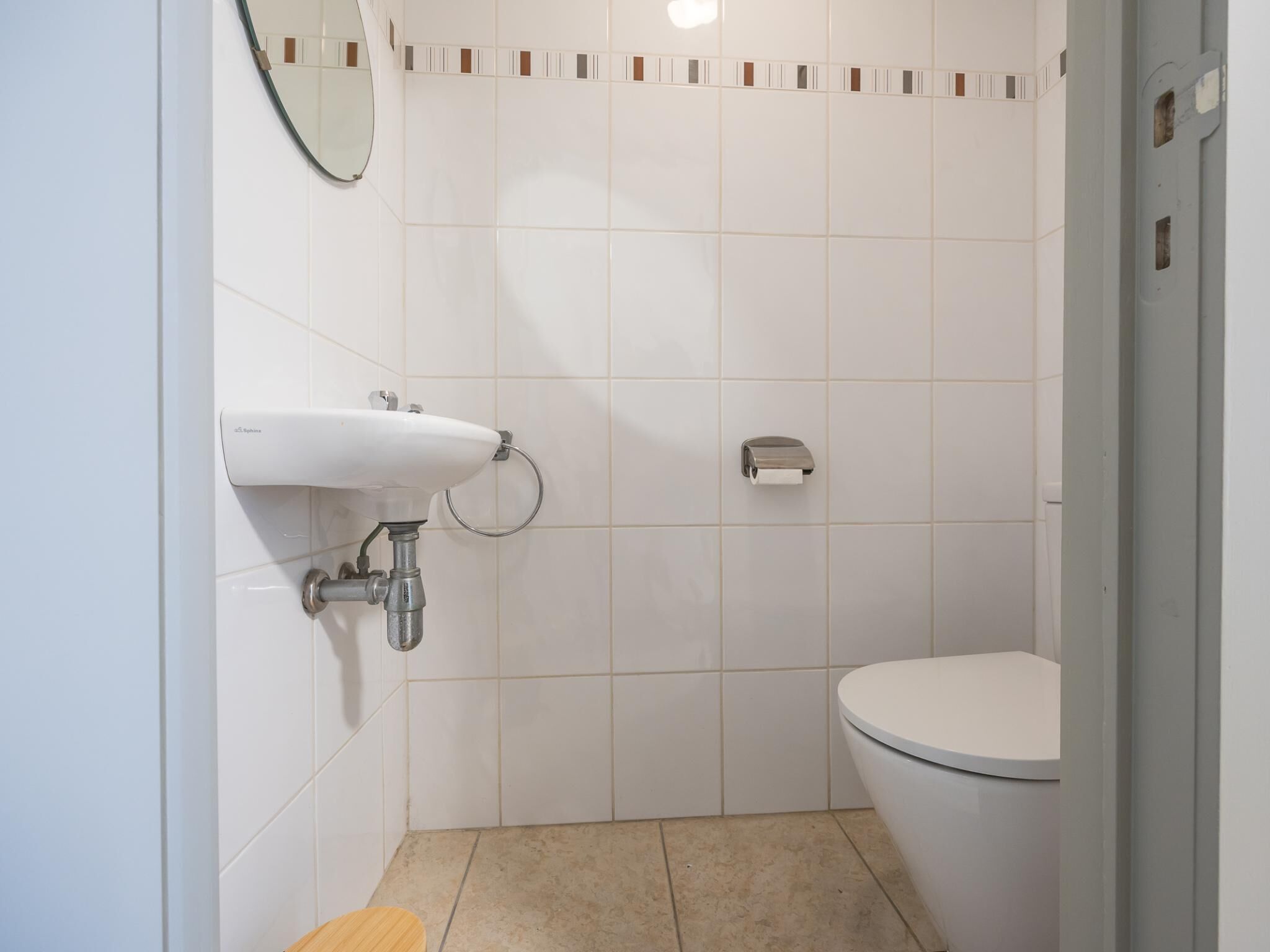 Une salle de bain avec un lavabo blanc, des toilettes et un miroir.