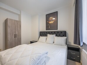 A bedroom with a bed, a wardrobe, a nightstand, and a wall-mounted artwork. - Ground-floor apartment for 6 people (Middelkerke)