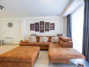 Ein Wohnzimmer mit Ecksofa, Couchtisch und Wandgerät zur Klimatisierung.