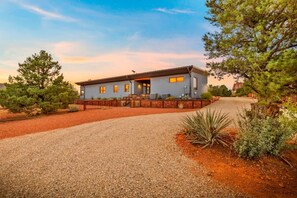 A modern two-story house with a gravel driveway, surrounded by trees and landscaping. - Rancho Rojo Casita - Kitchenette, Laundry, Views (Sedona)