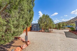 A gravel driveway leading to a small building with a blue door, surrounded by trees and a clear sky. - Rancho Rojo Casita - Kitchenette, Laundry, Views (Sedona)